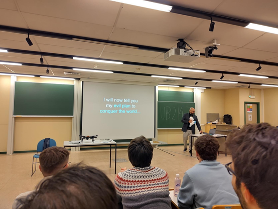 Slide showing "I will now tell you of my evil plan to conquer the world" with the presenter stroking a plushie unicorn