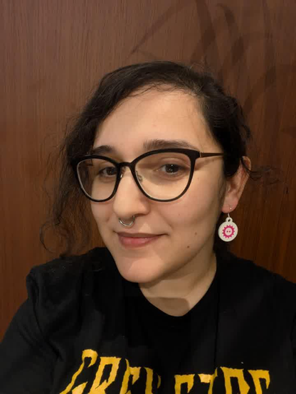 A woman wearing prusa 3D printed FOSDEM earrings.