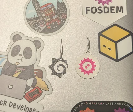 Prusa 3D printed FOSDEM and Grafana earrings.