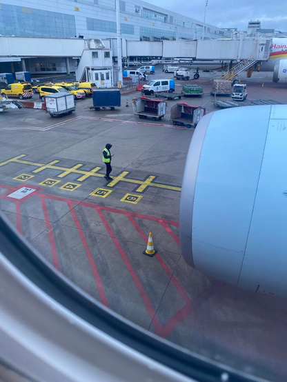 A view of from the plane window looking out at the tarmac at Brussels airport. À worker is seen looking at their phone