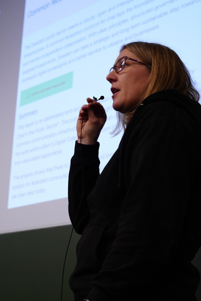 A portrait of Amandine speaking to the audience, holding a microphone in front of her mouth