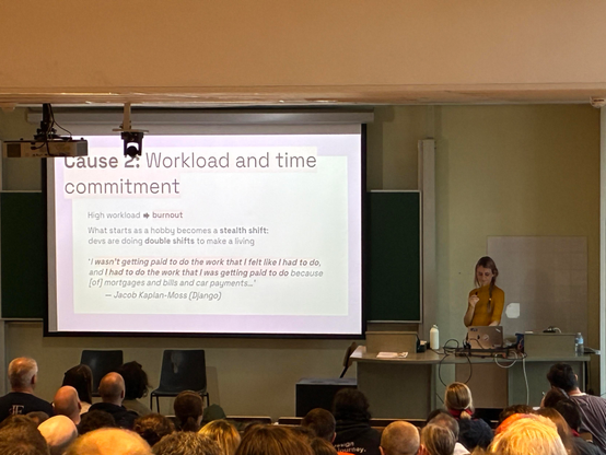 Miranda on stage next to a slide about Workload and time commitment
