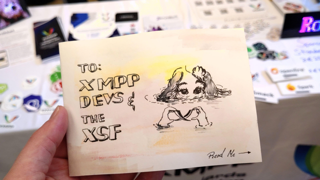 A self-made, hand-drawn (aquarell) folded letter with a mermaid holding the XMPP logo out of the water. Its adressed to XMPP Devs of the XSF.