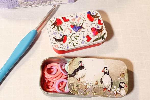 英国のイラストレーター、アレックス・クラーク氏によるデザインのブリキ製スライド缶が2つ。上のものは5羽の水彩のコマドリが配置されており、下のものは岩場にいる3羽のパフィンが描かれている。