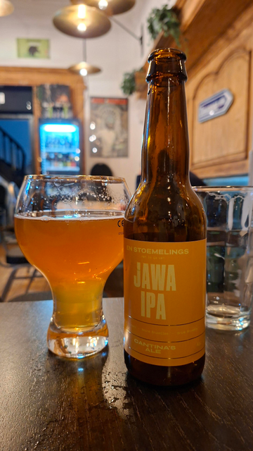 a bottle of En Stoemelings Jawa IPA Cantina's Ale poured into a Belgian beer glass inside a Brussels beer café