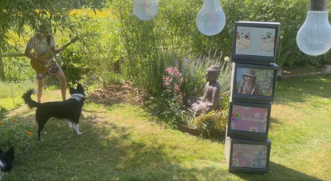 a still from a music video with a stack of CRT's showing various fediverse how too videos and a dog and a buddha statue