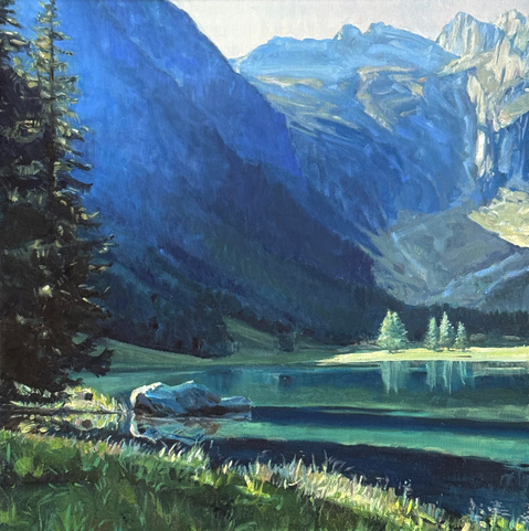 Ein spiegelglatter Bergsee von hohen Bergzinnen umgeben. Es ist Frühsommer, noch früh am Morgen und die ersten Sonnenstrahlen haben den See erreicht. Das Licht wirft noch lange Schatten, im smaragdblauen Wasser spiegeln sich die Lärchen von der anderen Seite des Sees. Links, vom Bildrand abgeschnitten stehen dunkle Tannen. Diel Luft wirkt frisch und vom Licht durchdrungen.