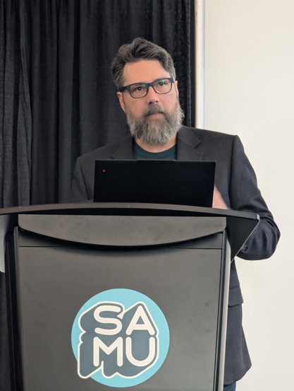 A photo of Robert Gehl speaking at a podium.