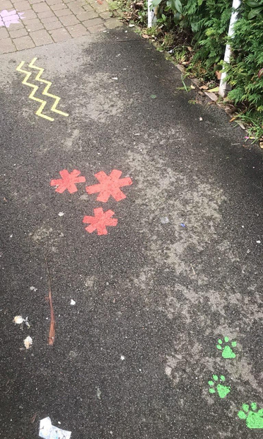 Three red asterisks in a triangle formation, painted on a pavement between some other designs.