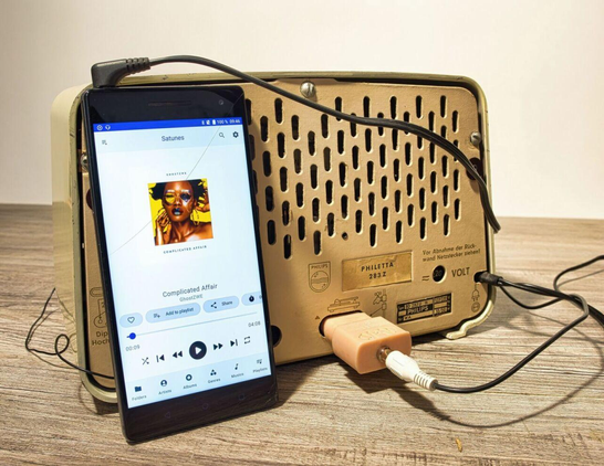 Phillips Philetta Radio Rückseite mit Smartphone an TA Anschluss mittels NF Stecker von Neufeldt & Kuhnke angeschlossen.
Das Diesplay des Smartphones zeigt einen MP3 Player.