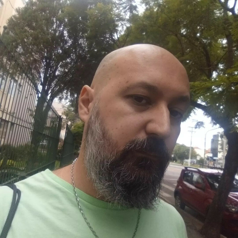 That's me. A bald latino light skinned skinny guy in my mid 40s, with a big nose and a black beard turning gray. I'm wearing a green t-shirt, a small chain in my neck and I'm in a sidewalk surrounded by trees.