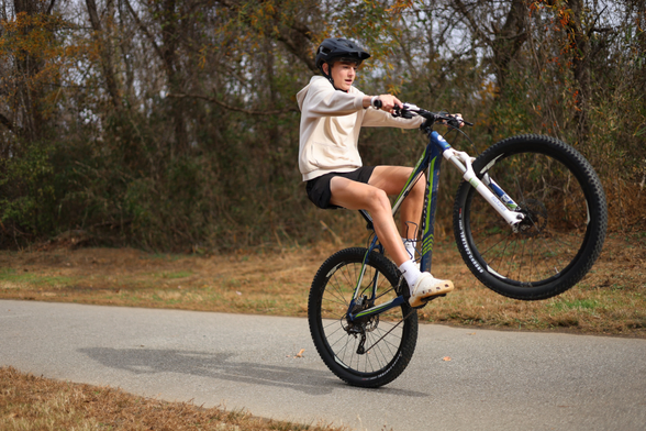 A young lad shreddin' it up, being "rad", and popping a wheelie on his bicycle contraption.