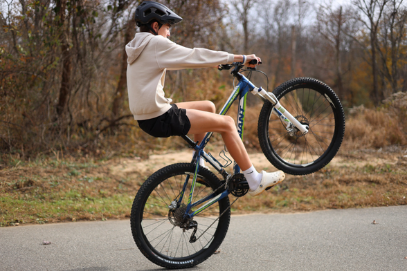 A young lad shreddin' it up, being "rad", and popping a wheelie on his bicycle contraption.