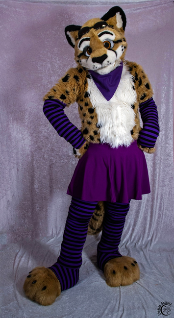 In fursuit standing in a sassy pose wearing purple stockings, arm warmers, and skirt