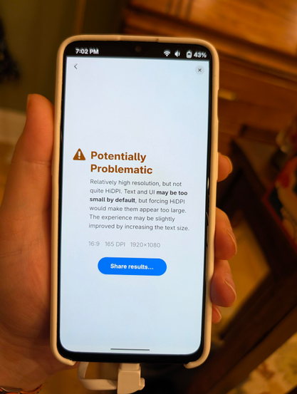 A phone showing the result for the display in the other image. It reads: 

“Potentially Problematic. 
Relatively high resolution, but not quite HiDPI. Text and UI may be too small by default, but forcing HiDPI would make them appear too large. The experience may be slightly improved by increasing the text size.” 

Below, it has the specs (16:9, 165 DPI, 1920×1080) and a prominent button to “share results.”
