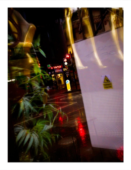 Early morning photograph showing colorful neon reflections and lighting through the window of Brazilian Waxing Company on Oxford Road Manchester, with purple, pink and red lights creating an abstract urban composition.