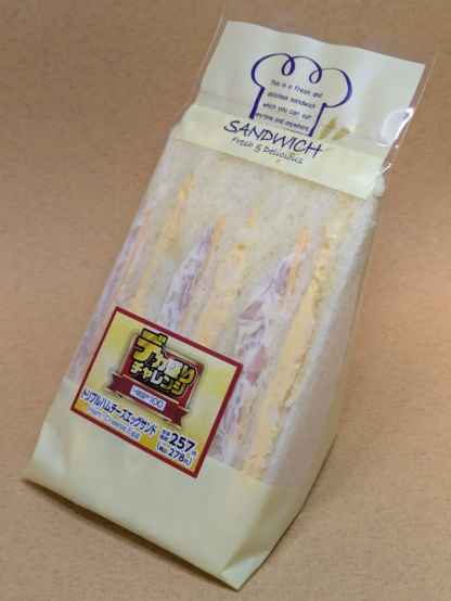 ローソンストア100の「トリプルハムチーズエッグサンド」。「デカ盛りチャレンジ」の一品で通常2組の三角サンドウィッチが1組増量されている。