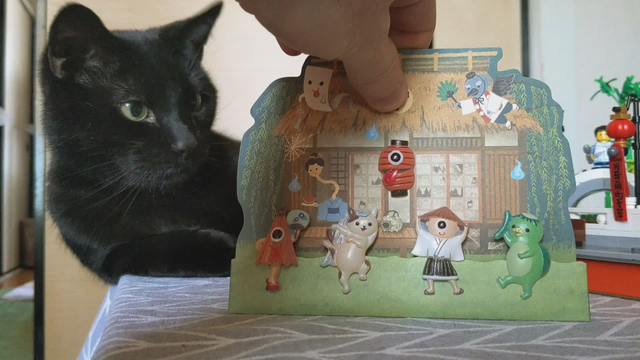 Percy the cat admires a musical card featuring Japanese yokai.