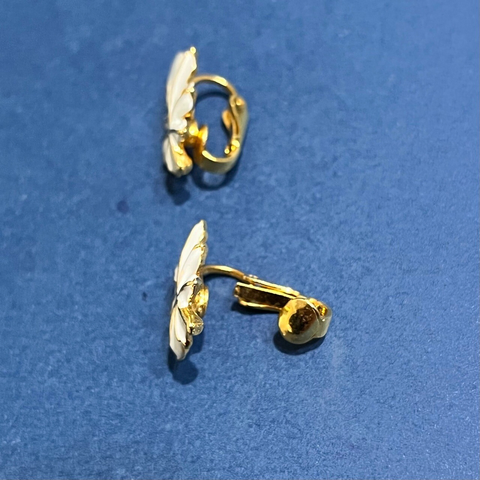 白い塗装が施された、楓（カエデ）のような葉っぱモチーフのイヤリング一対。縁取りと葉脈はゴールド。横から見たクリップ金具の形状がわかる配置。