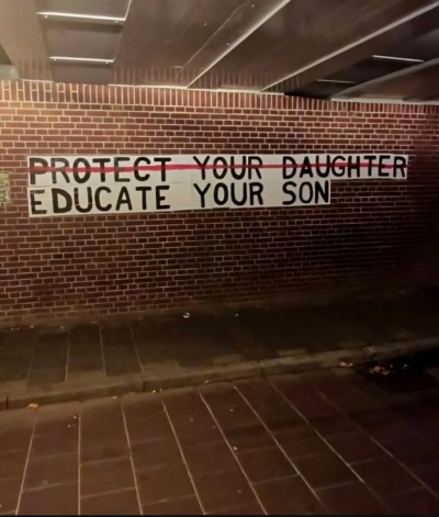 Mural on brick wall with words "Protect your daughter" stricken out.
Below it says, "Educate your son"