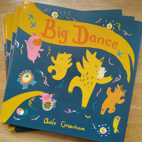 A small stack of freshly published copies of Big Dance. Cover is all the characters dancing on a dark blue bg, with the words Big Dance in red/orange on a warm yellow ribbon. There are brightly coloured confetties and colour bursts, and blue swallows flying.