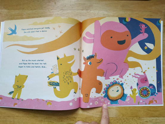 All the characters are getting ready for the Big Dance. Everyone is excited and happy. Fancy Chicken is smiling. Whizz has the Ribbon held high and is rolling along in their brightly coloured wheelchair. Text says 'Pippa watched everyone get ready. She still didn't feel a dance. but as the music started and Pippa felt the beat, her tail began to tickle and twitch. And...' Pippa watches everyone with a curious expression on her face.
