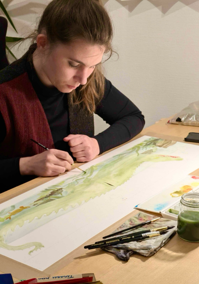 A photograph of me sitting at a desk, painting an double A3 sized crocodile.