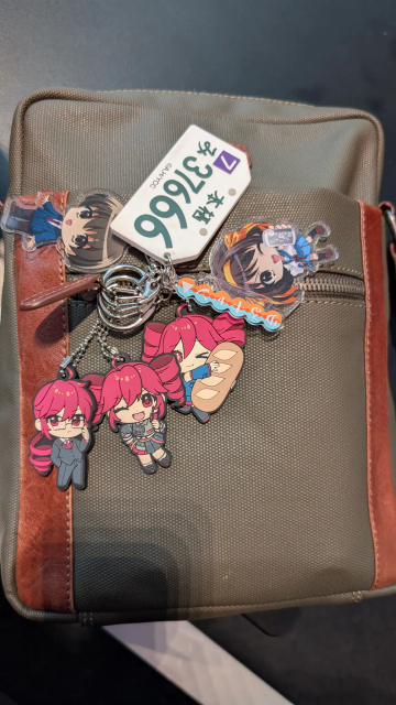 A green bag with 6 keyrings, 3 of them are Kasane Teto, two are Haruhi characters and one is a Yuru Camp theme. 