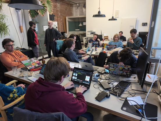 About 10 hackers sitting around 3 tables at Cultivation space hacking and discussing.