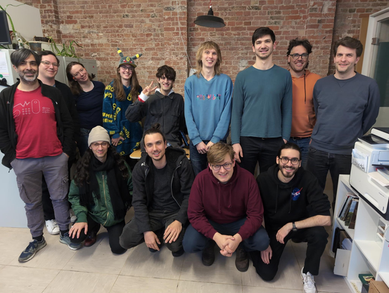 13 hackers in two rows lining up for a group photo in the back at Cultivation Space.