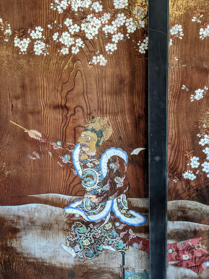 A wooden door in the palace at Ninna-ji depicting a gagaku performer beneath cherry blossoms.