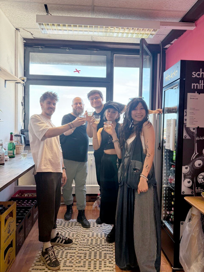 The founders of pixel.forest() - Bileam Tschepe, Felix Betzenbichler, Christoph Ignaz Kirmaier, Ploypapus Phosri, Marta Pang -  standing together in the kitchen of the space, raising drinks shortly before the opening event in September 2025.