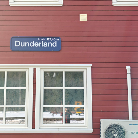 White framed windows on a red wooden building with a blue sign that says Dunderland, altitude 127m