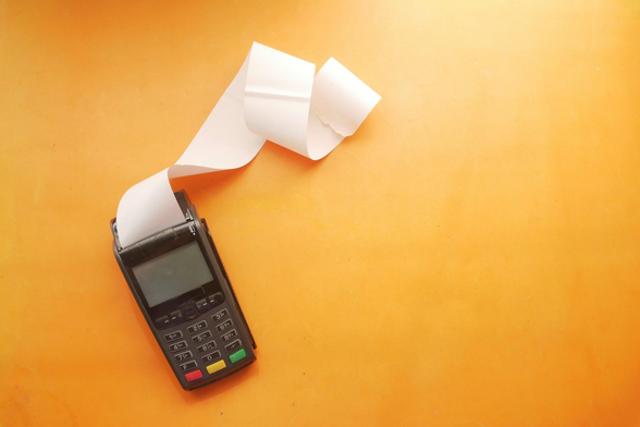 Photo of a point of sale device on an orange tabletop. The device has a long piece of receipt paper hanging out of the printer portion.

Image credit: Towfiqu barbhuiya on Unsplash (https://unsplash.com/photos/a-cell-phone-sitting-on-top-of-a-table-next-to-a-roll-of-paper-xkArbdUcUeE)