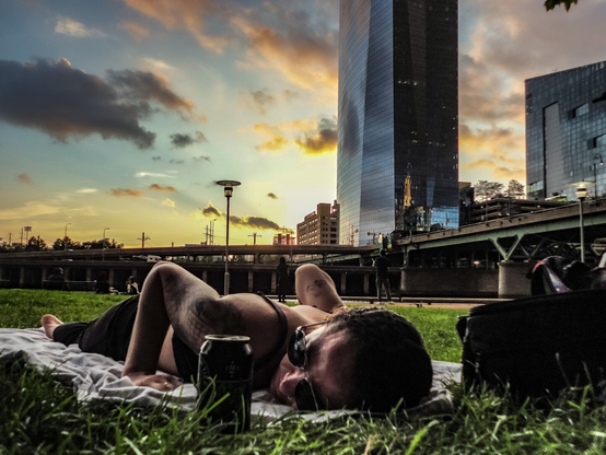woman lying on a blanket in the grass along the Schuylkill River at sunset