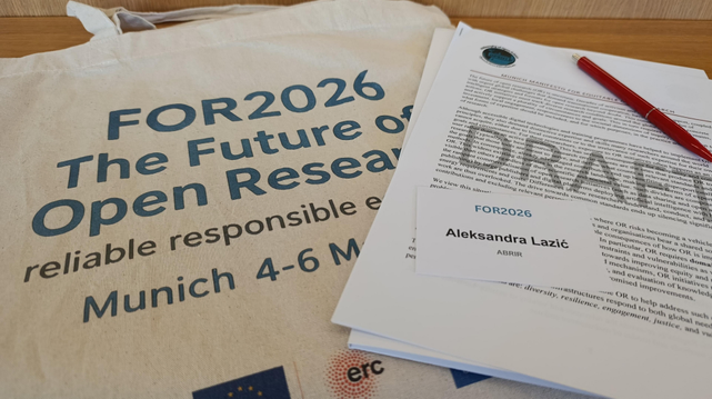 A photo showing a conference tote bag with the words "FOR2026 The Future of Open Research, Munich" printed on it; next to it is a printed draft of the Munich manifesto, a red pen, and a name tag saying "Aleksandra Lazic, ABRIR".