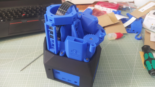 A pile of blue and black components starting to be assembled. The openflexure microscope logo is visible debossed into the side of one printed part. 