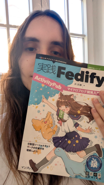 a selfie, Nicole’s holding the Fedify book with Ai-chan and Mastodon and Fedify mascots on the cover.