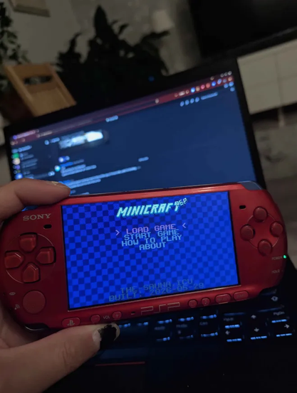 me holding a radiant red psp in front of a laptop showing the minicraft psp title screen
