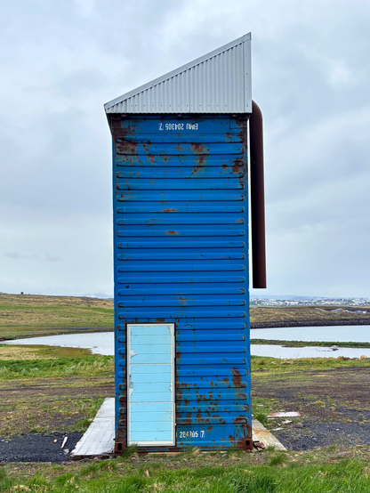 A strange blue tower with a light blue door.