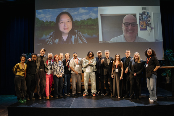 A collection of people on stage at the Open Social Awards. The winners are holding small glass trophies. 