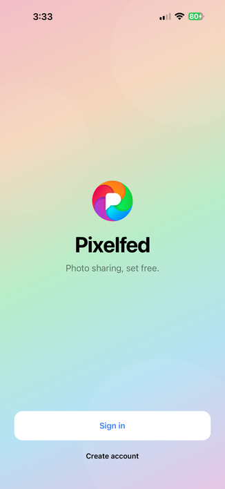 Screenshot of the new Pixelfed mobile app landing screen on iOS with a gradient background consisting of the logo colours with the Pixelfed logo and text below that says "Pixelfed" and below that in smaller text "Photo sharing, set free." with a Sign in and Create account button at the bottom of the screen