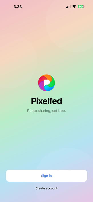 Screenshot of the new Pixelfed mobile app landing screen on iOS with a gradient background consisting of the logo colours with the Pixelfed logo and text below that says "Pixelfed" and below that in smaller text "Photo sharing, set free." with a Sign in and Create account button at the bottom of the screen