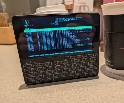 An A64 based Pocket P.C. is seen running htop in a cafe