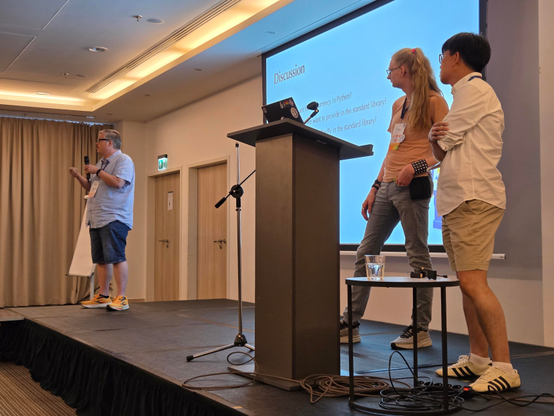 Tobias answering a question, Donghee and Fridtjof on stage. 