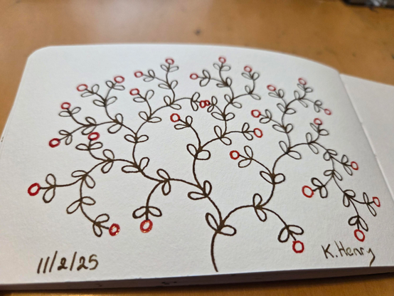 Hand drawn generative/procedural art in ink on an open page of my sketchbook. The abstract pattern looks a bit like a rose bush with flowers