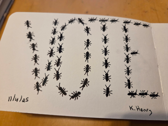 Hand drawn generative/procedural art in ink on an open page of my sketchbook. The abstract pattern looks like ants have lined up to spell the word "VOTE"