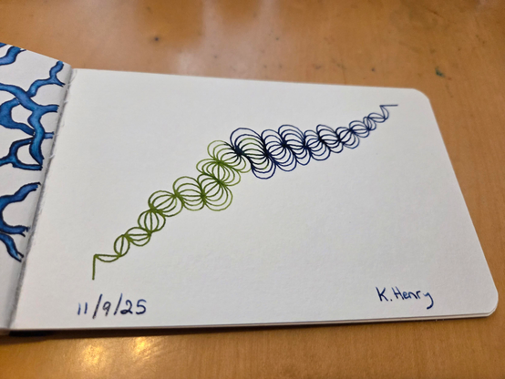 Hand drawn generative/procedural art in ink on an open page of my sketchbook. The pattern looks a bit like a strange creature or a broken hair scrunci.