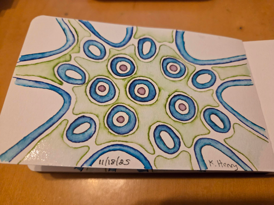 Hand drawn generative/procedural art in ink on an open page of my sketchbook. The abstract pattern looks a bit like something that might be visible under a microscope.