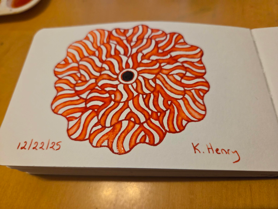 Hand drawn generative/procedural art in ink on an open page of my sketchbook. The abstract pattern is a flower.
